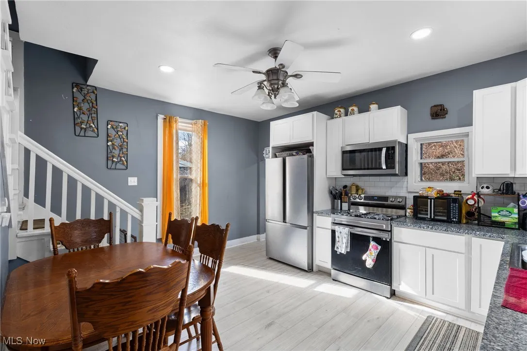 Kitchen featuring appliances with stainless steel finishes, white cabinetry, a ceiling fan, dark stone counters, and recessed lighting