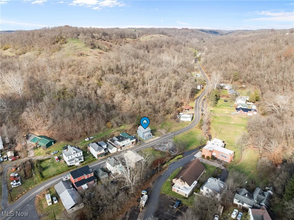 View of property location featuring a heavily wooded area and nearby suburban area
