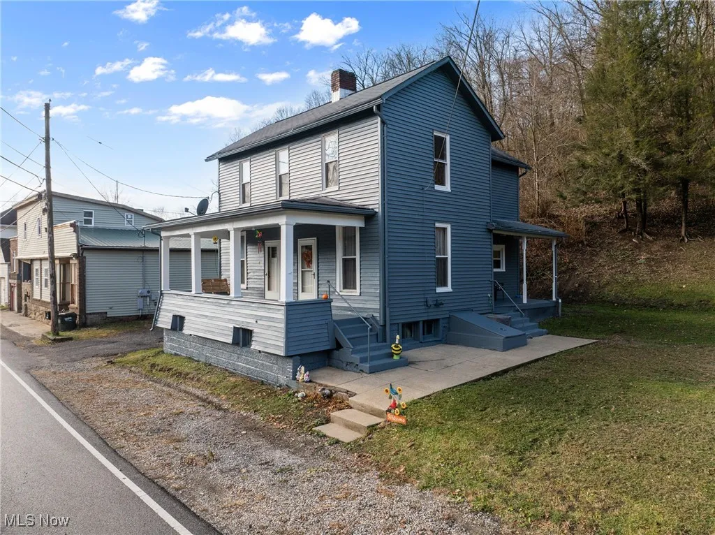 View of front of home featuring a porch, a chimney, and a front lawn