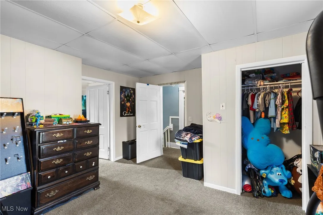 Carpeted bedroom with a closet and wooden walls