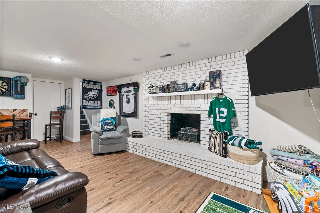 Living area featuring a fireplace, light wood-style floors, a textured ceiling, and stairway