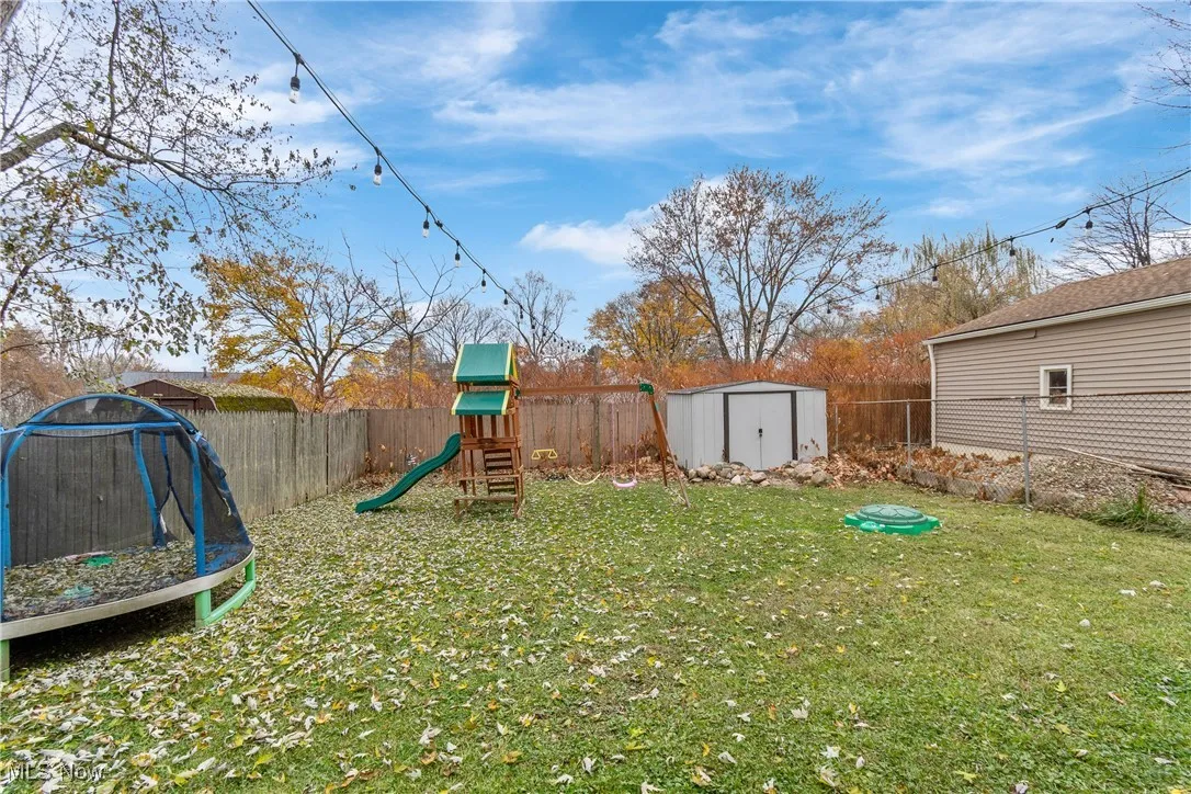 Fenced backyard with a shed, a trampoline, and a playground