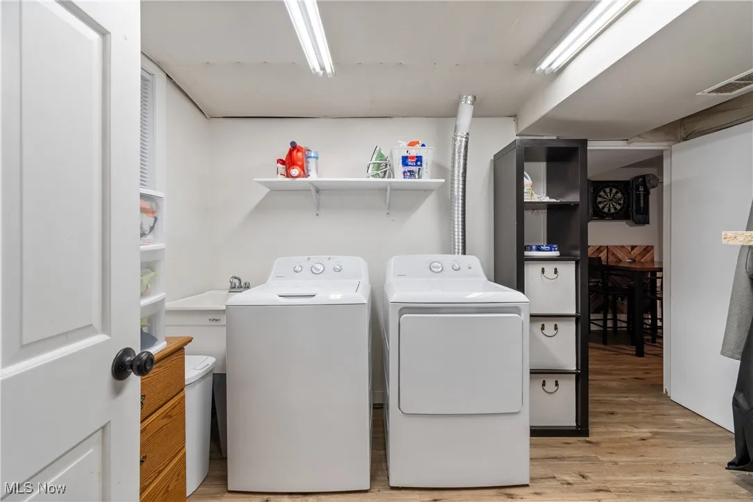 Laundry area featuring washing machine and clothes dryer and light wood-type flooring