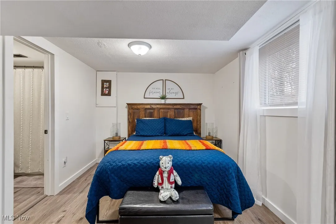 Bedroom with a textured ceiling and light wood finished floors