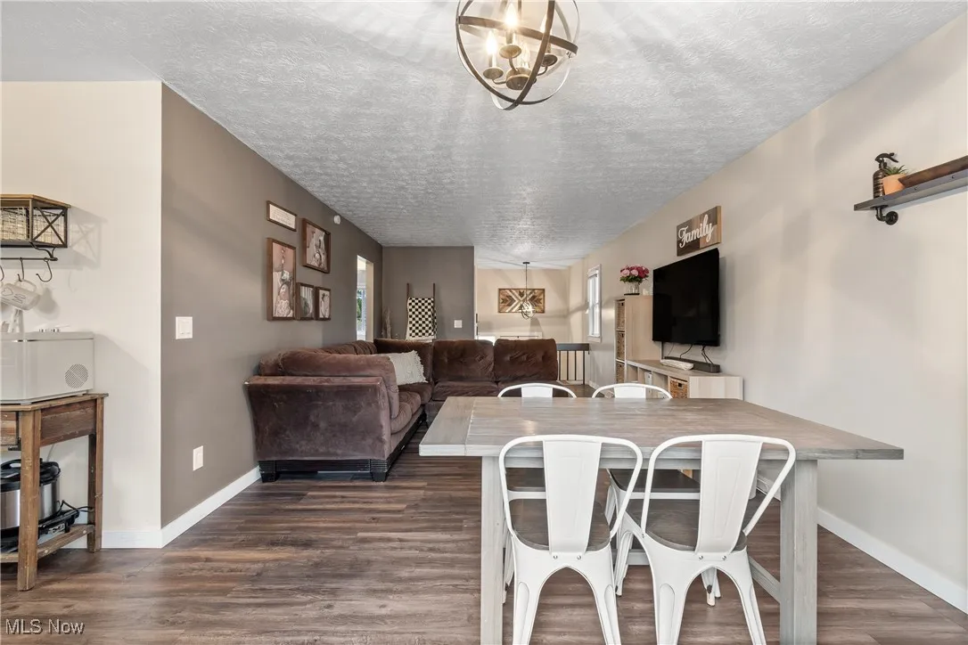 Dining space featuring dark wood-style flooring, a textured ceiling, and a chandelier