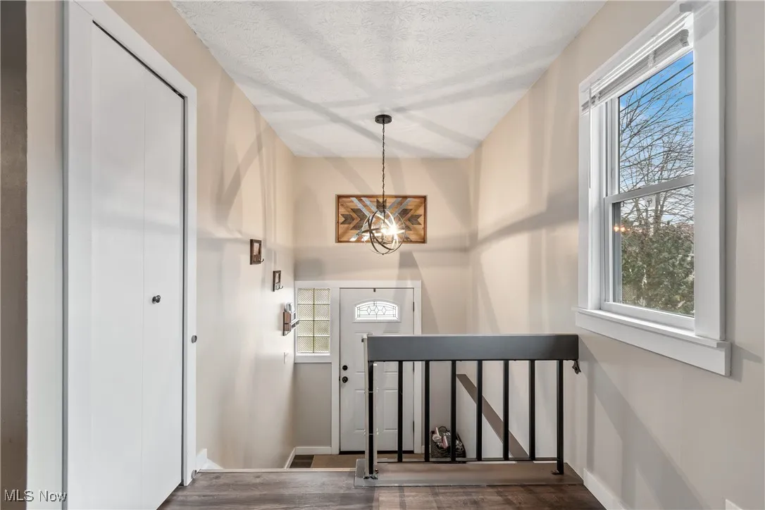 Foyer entrance with wood finished floors, a chandelier, and a textured ceiling