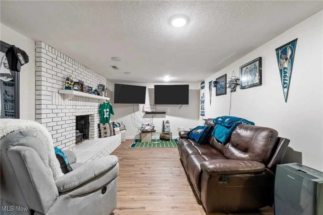 Living area with a textured ceiling, a fireplace, and wood finished floors