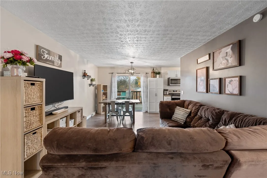Living room featuring wood finished floors, a textured ceiling, and a chandelier