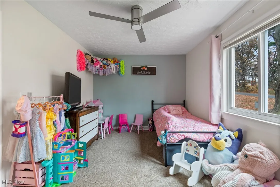 Carpeted bedroom featuring a ceiling fan and a textured ceiling