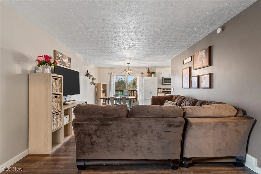 Living room with a textured ceiling and dark wood-style flooring