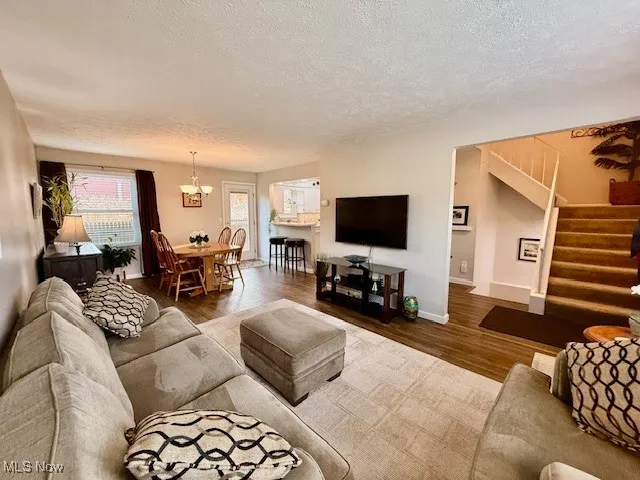 Living area with LVP waterproof dark walnut finished floors, a textured ceiling  Foyer area  and stairway to finished basement, bathroom and laundry room, and 3 spacious bedrooms upstairs.