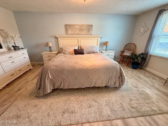 Extra spaciousa master bedroom with light wood waterproof finished floors and a textured ceiling