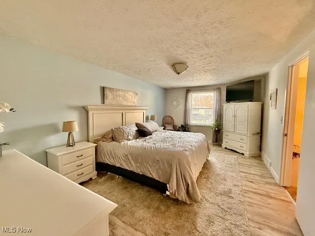 Spacious Master Bedroom featuring a textured ceiling and light wood-style flooring