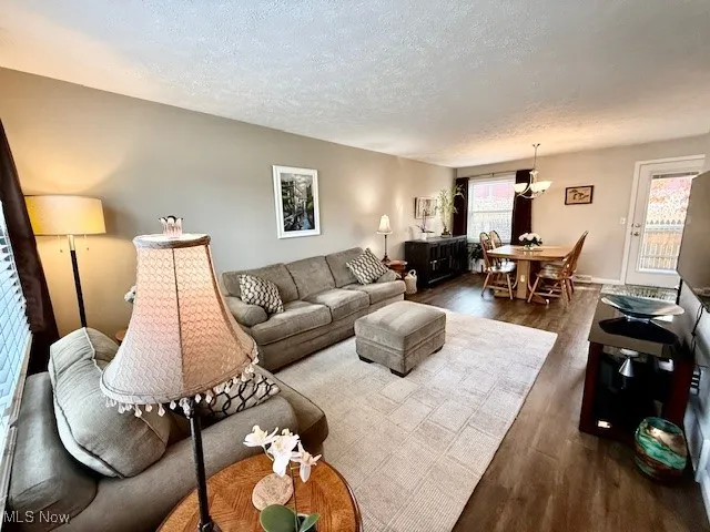 Living room with LVP dark walnut wood-style, waterproof floors, and a textured ceiling.