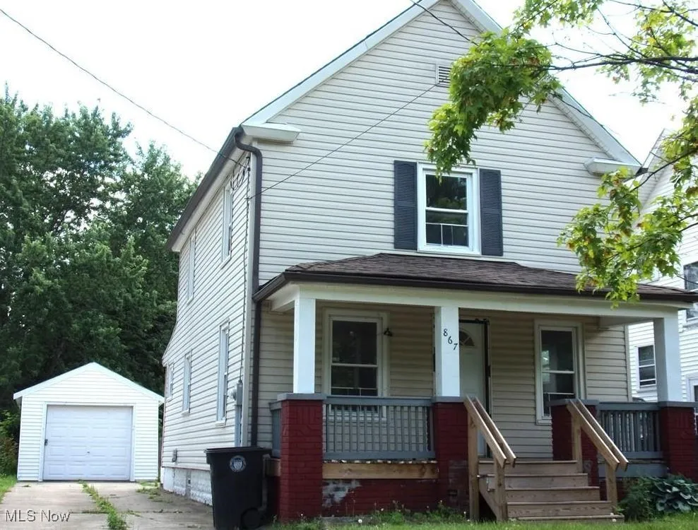 View of front of house featuring an outbuilding, covered porch, a detached garage, and concrete driveway