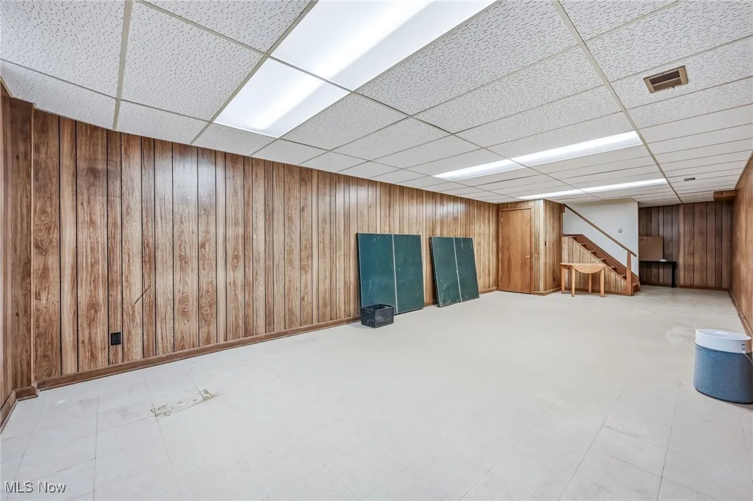 Finished recreation area/ playroom with wood walls and laminate flooring. Full bath around the stairs