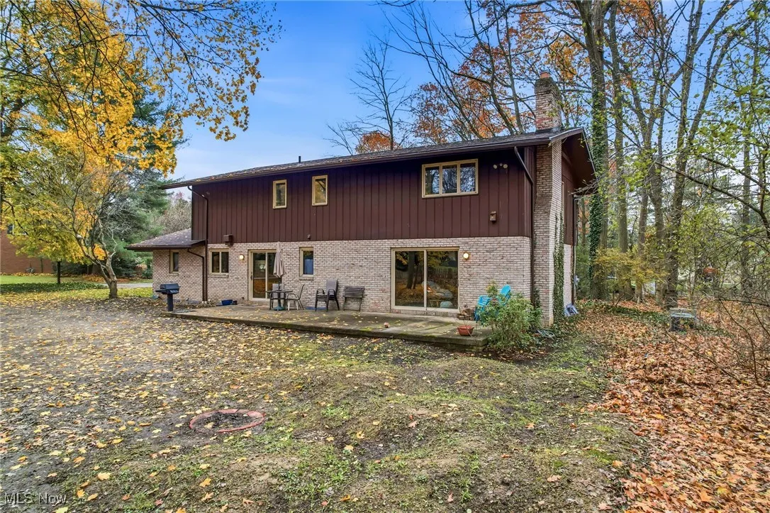 Back of house with a chimney and brick siding