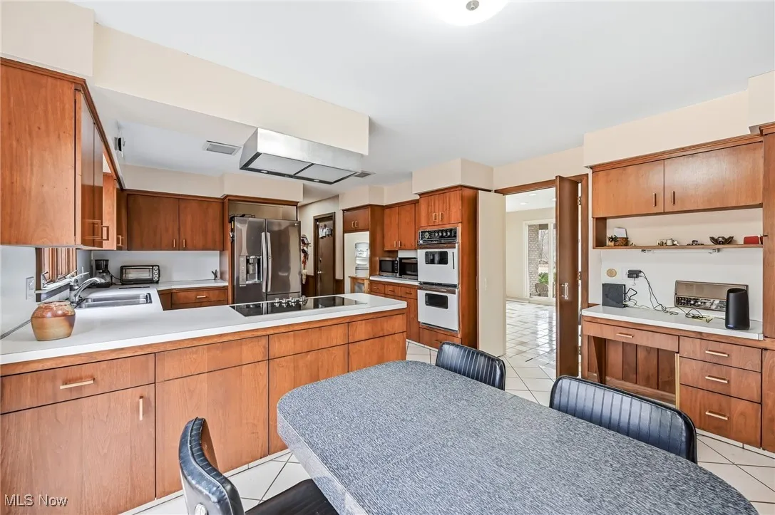 Kitchen featuring new cooktop and exhaust fan, double wall ovens and a desk area