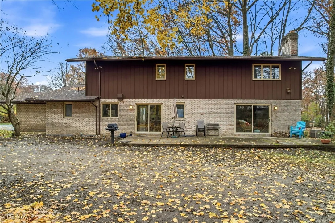 Back of house with a large patio, a chimney, and brick with a set of sliding glass doors