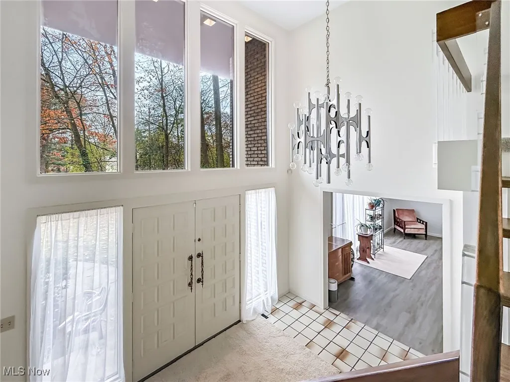 Entrance foyer with a chandelier, a towering ceiling, healthy amount of natural light, and tile patterned flooring
