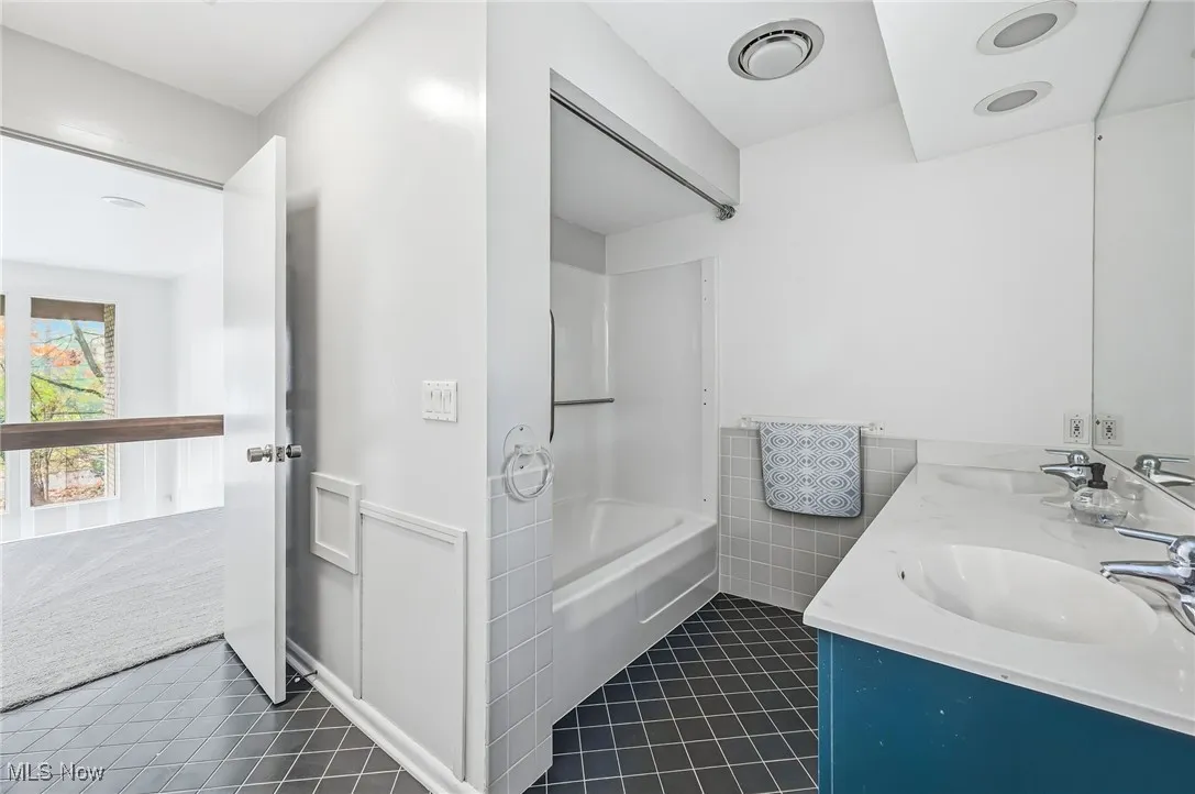 Bathroom with double vanity and bathing tub / shower combination