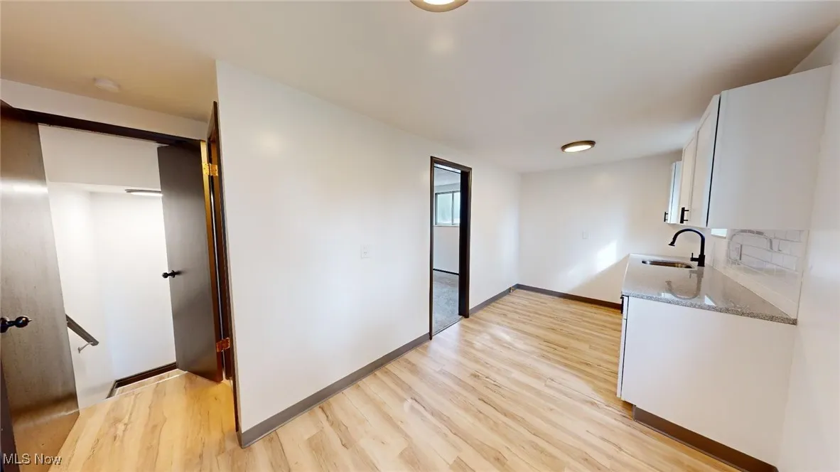 Kitchen with light stone countertops, white cabinetry, and light wood finished floors