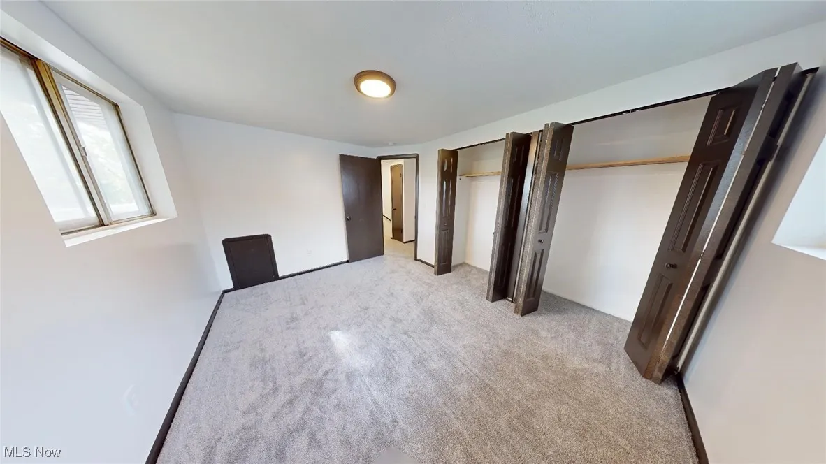 Unfurnished bedroom with two closets and light colored carpet