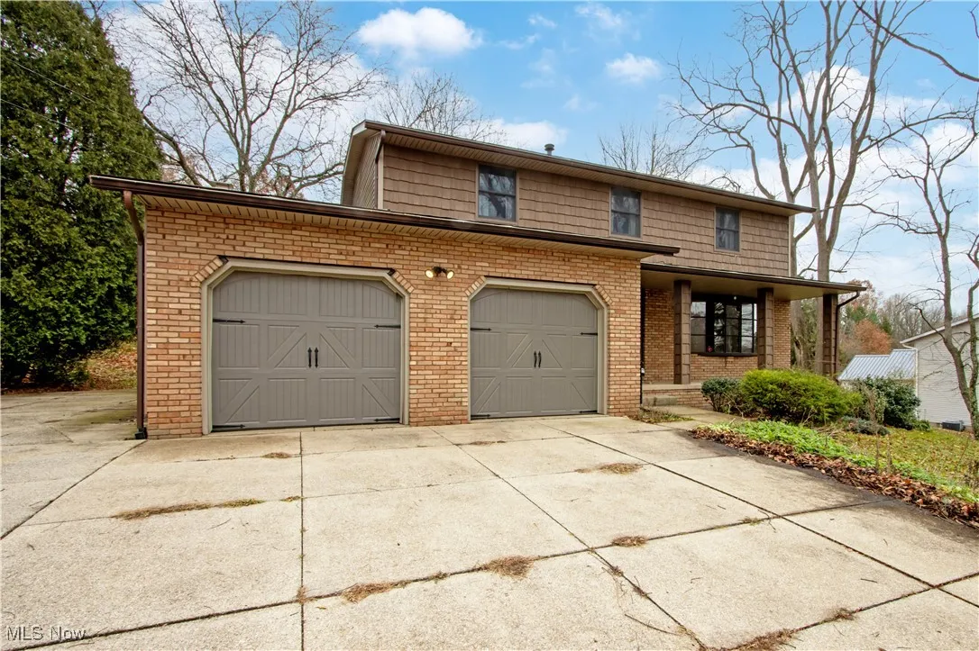 Traditional-style home with driveway, brick siding, and an attached garage