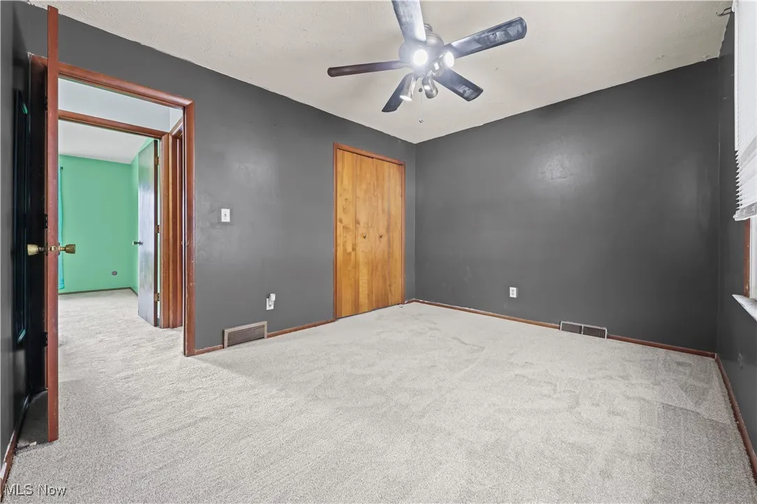 Unfurnished bedroom featuring carpet flooring, a ceiling fan, and a closet