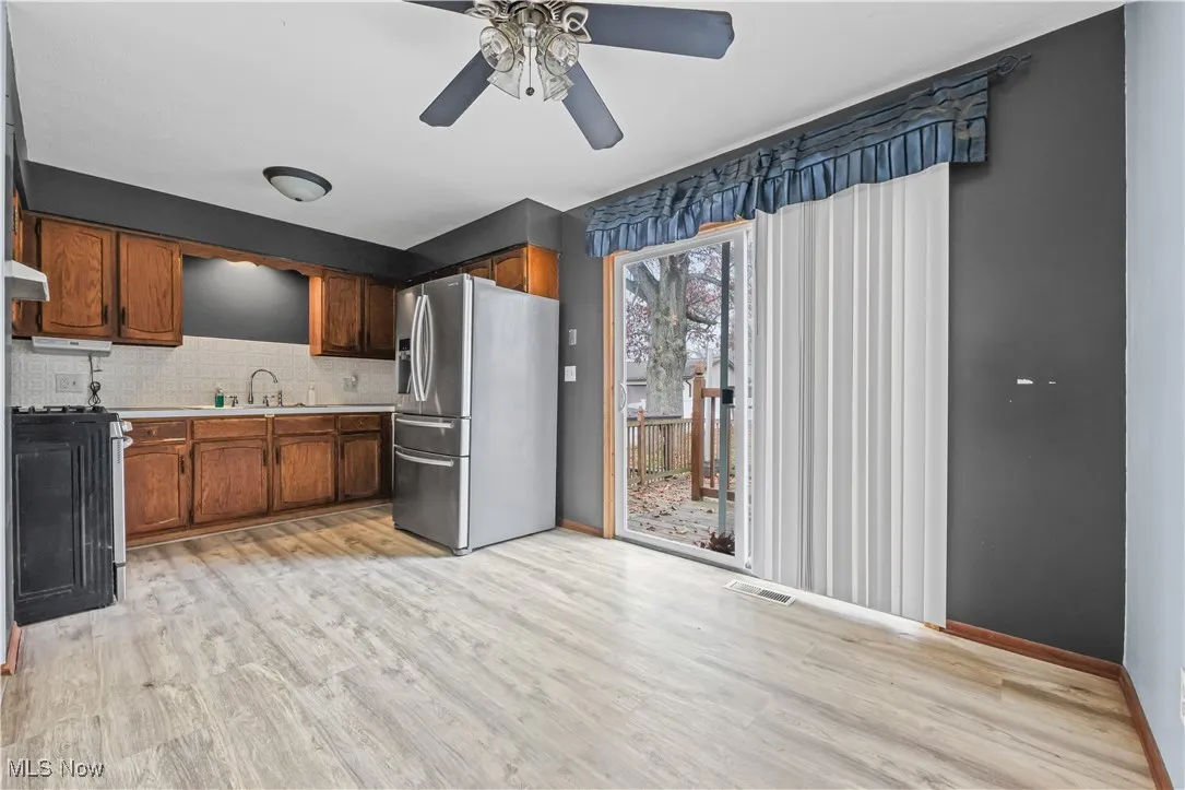 Kitchen featuring appliances with stainless steel finishes, light countertops, light wood-style flooring, tasteful backsplash, and brown cabinets