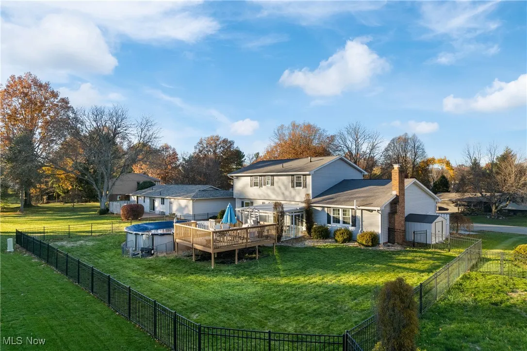 Back of house featuring a deck, a storage shed, and a fenced backyard