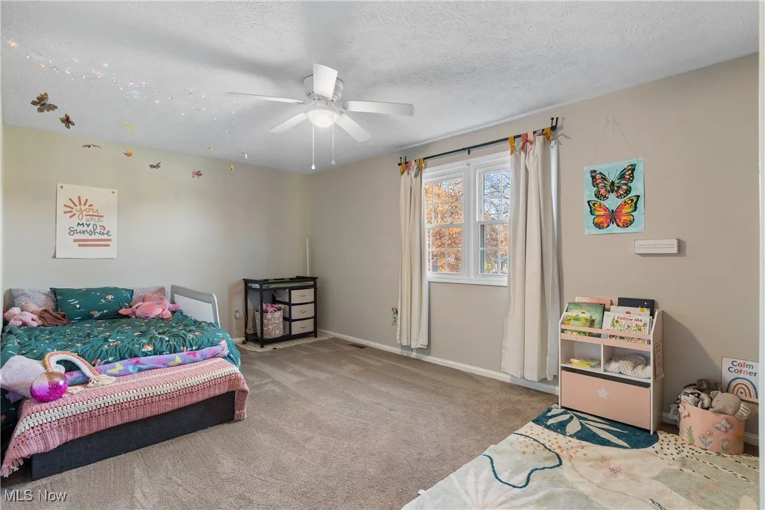 Bedroom featuring carpet flooring, ceiling fan, and a textured ceiling