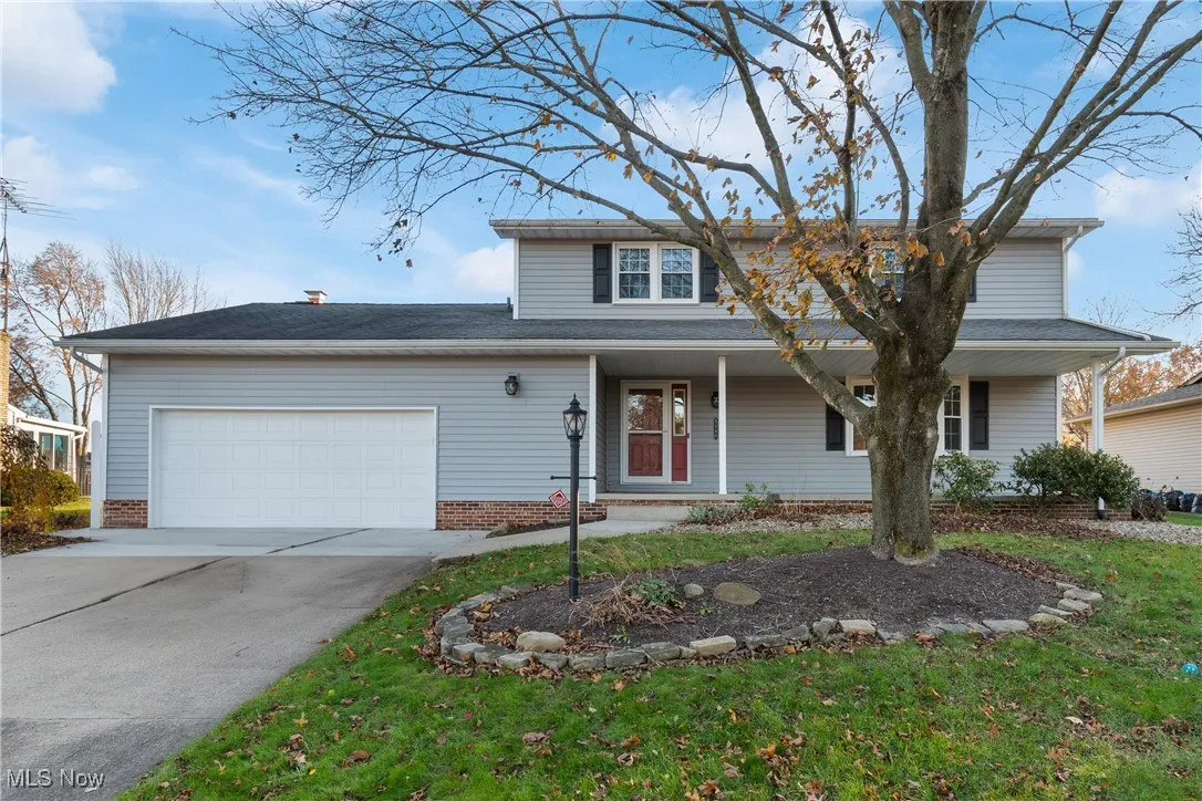 Traditional-style home featuring covered porch, concrete driveway, a garage, and a front lawn