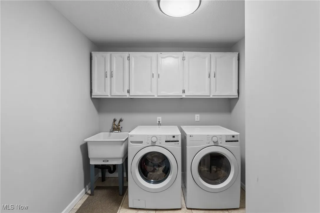 Washroom with cabinet space, independent washer and dryer, light tile patterned floors, and a textured ceiling