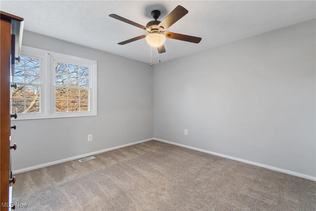 Spare room featuring light carpet, a textured ceiling, and ceiling fan