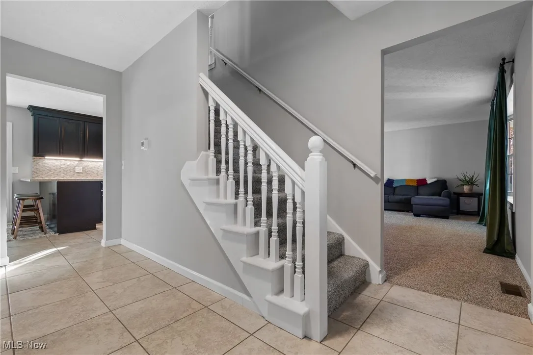 Stairway featuring carpet and tile patterned flooring