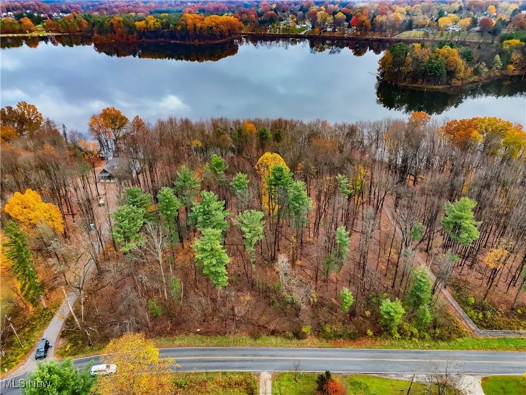 Drone / aerial view of a heavily wooded area and a nearby body of water