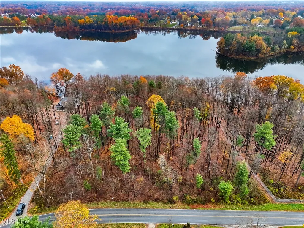 Aerial view of property's location featuring a forest and a nearby body of water