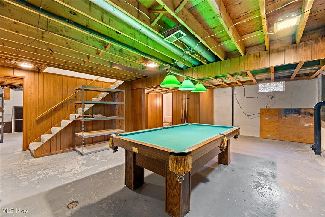 Rec room featuring concrete block wall, billiards table, unfinished concrete flooring, and wooden walls