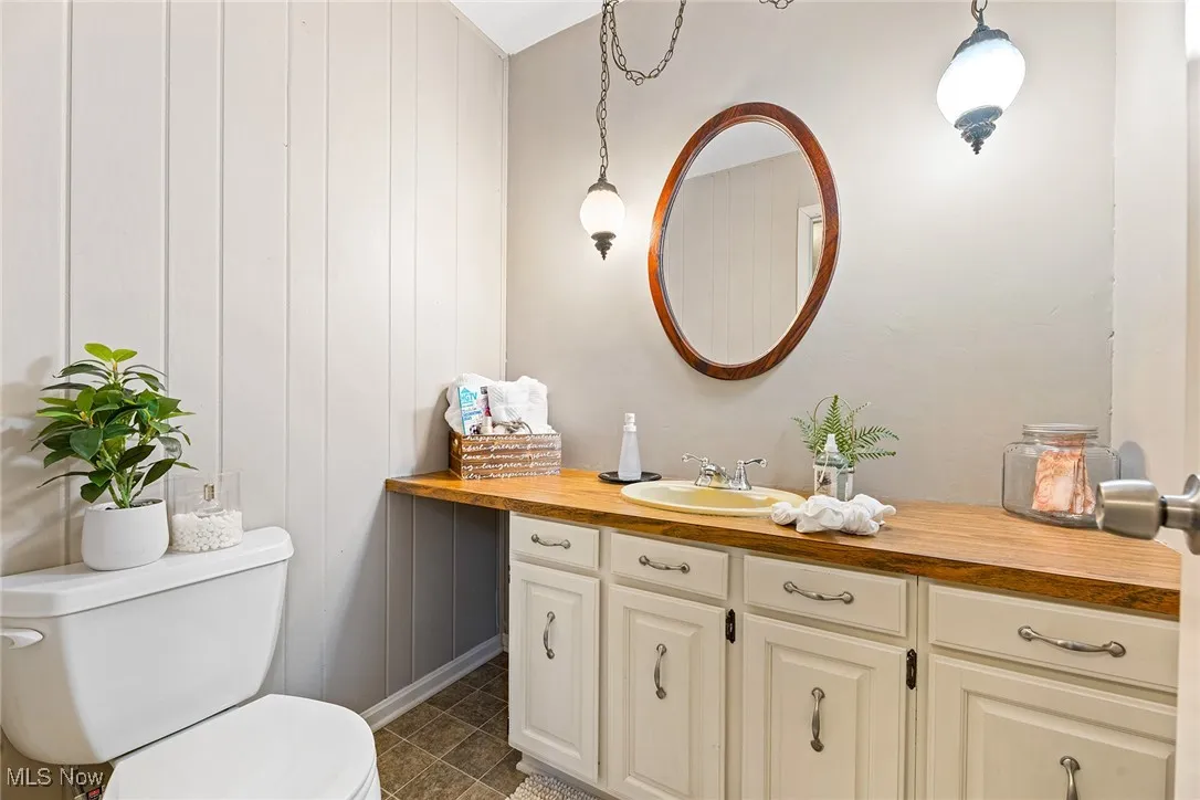 Bathroom featuring vanity, dark tile patterned flooring, and wood walls