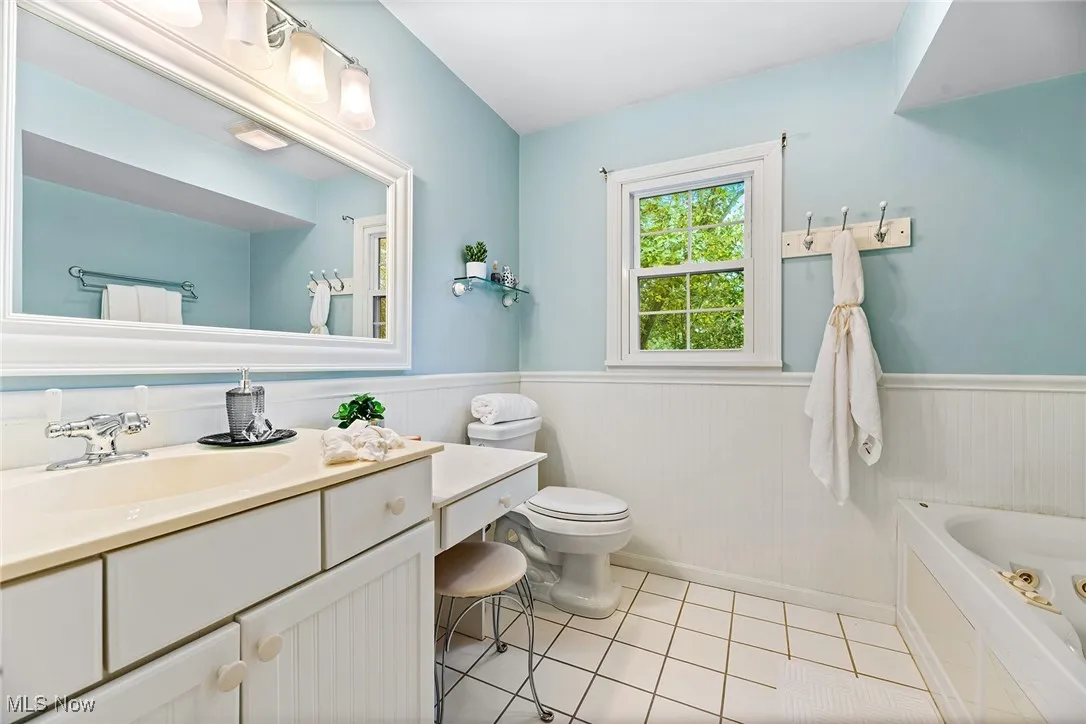 Bathroom featuring wainscoting, vanity, a bath, and light tile patterned flooring