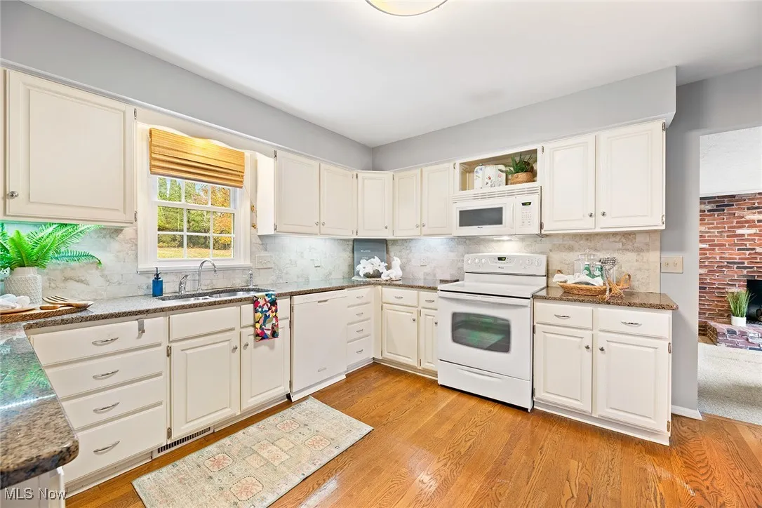 Kitchen featuring white appliances, dark stone counters, light wood-type flooring, and open shelves