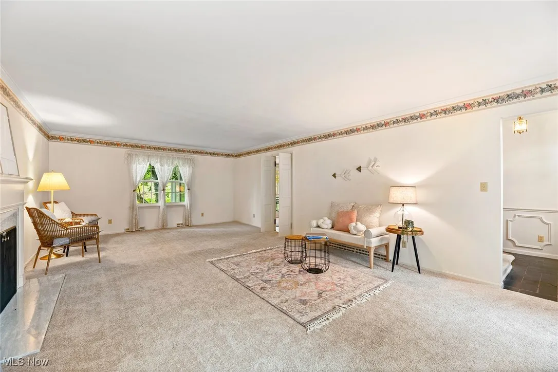 Living area with a fireplace, carpet flooring, and ornamental molding