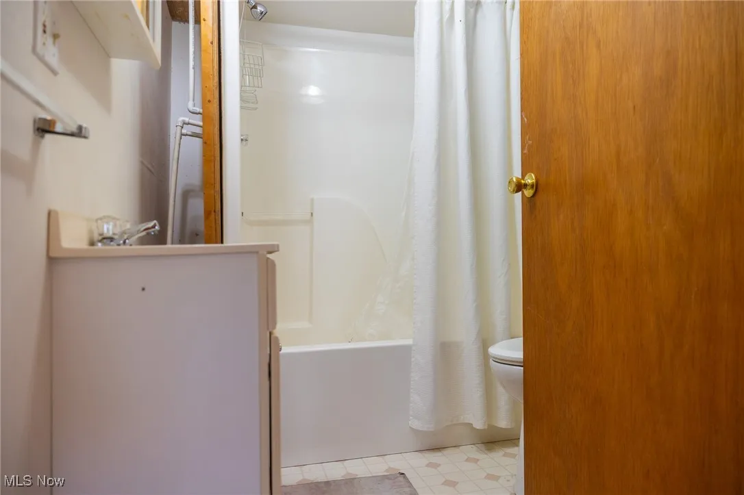 Full bath featuring shower / bathtub combination with curtain and light floors