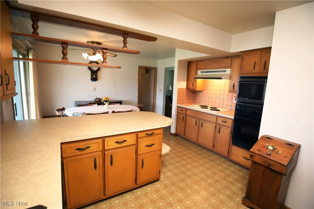 Kitchen with light floors, light countertops, tasteful backsplash, and brown cabinets