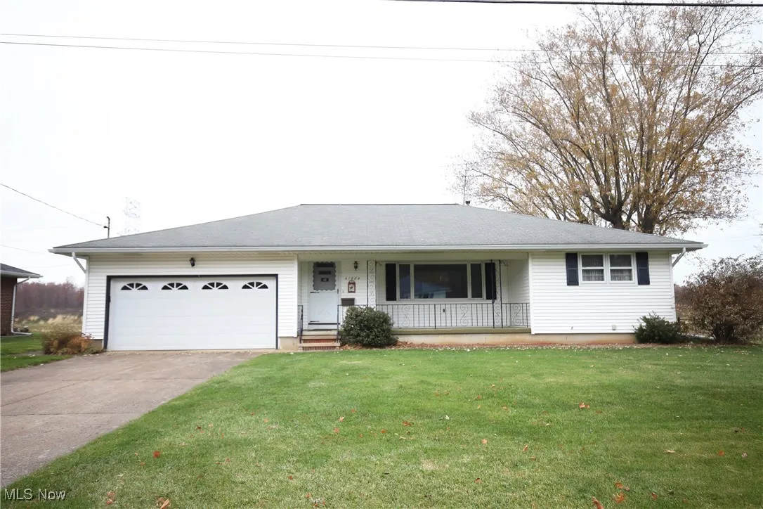 Ranch-style house with covered porch, a front lawn, a garage, and driveway