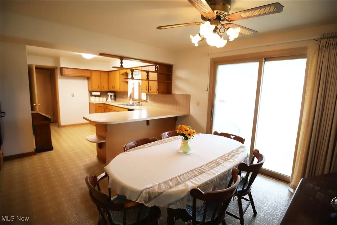 Dining room with a ceiling fan and light colored carpet