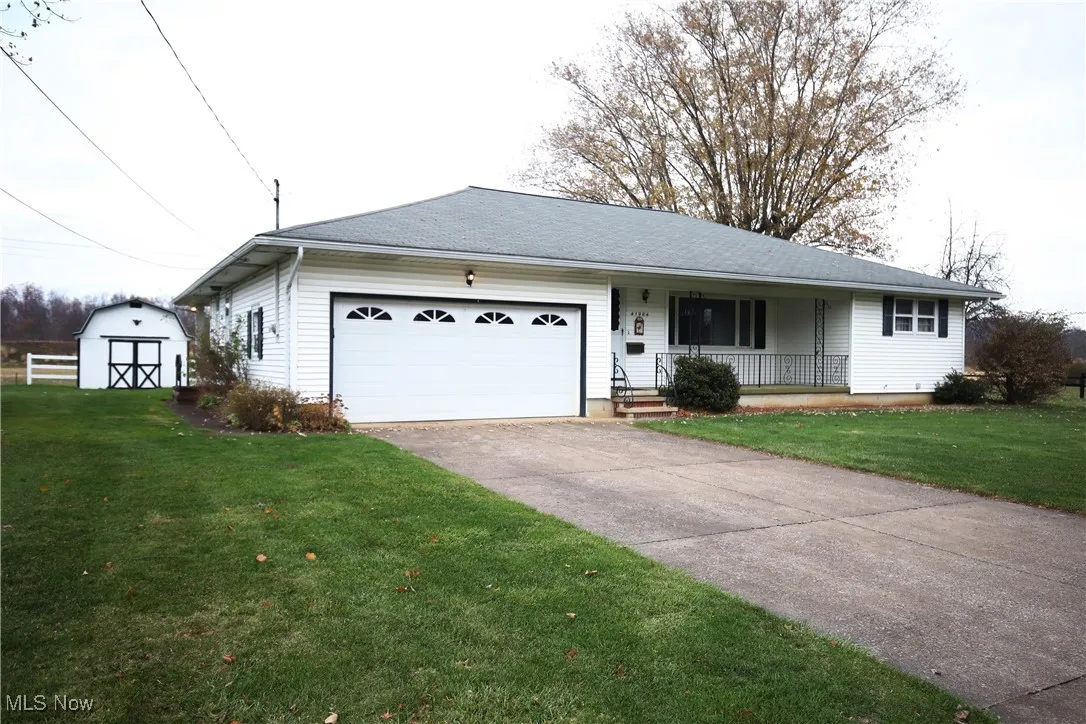 Single story home with covered porch, a garage, a front lawn, driveway, and a shingled roof