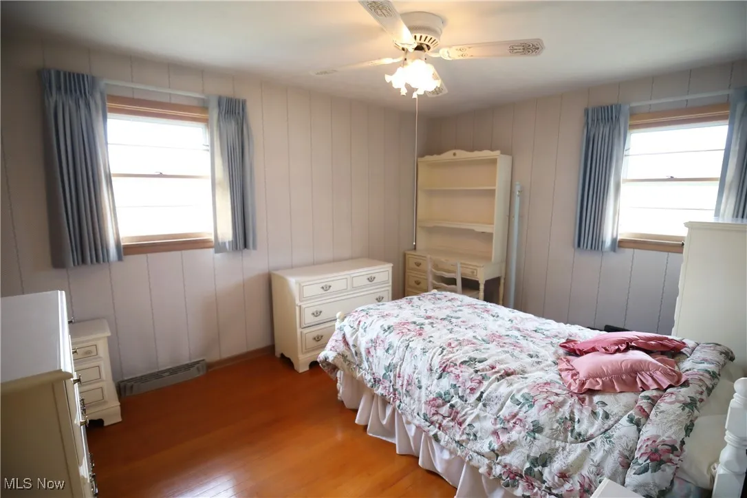 Bedroom with light wood-style flooring, multiple windows, and ceiling fan