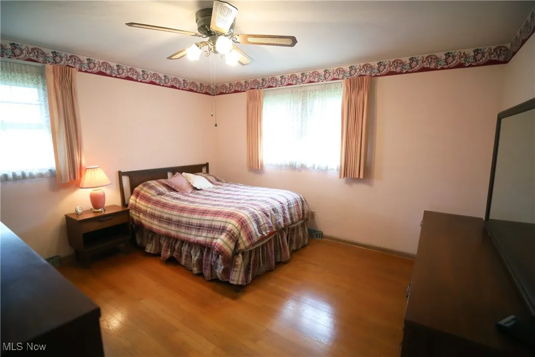 Bedroom with multiple windows, wood finished floors, and ceiling fan